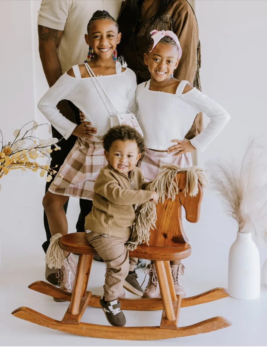 The Kemp children posing together, the youngest on a wooden rocking horse